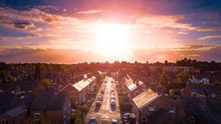 Sun rising above a traditional British housing estate with countryside in the background