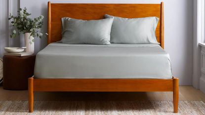 Wooden bed frame with sage green bedding