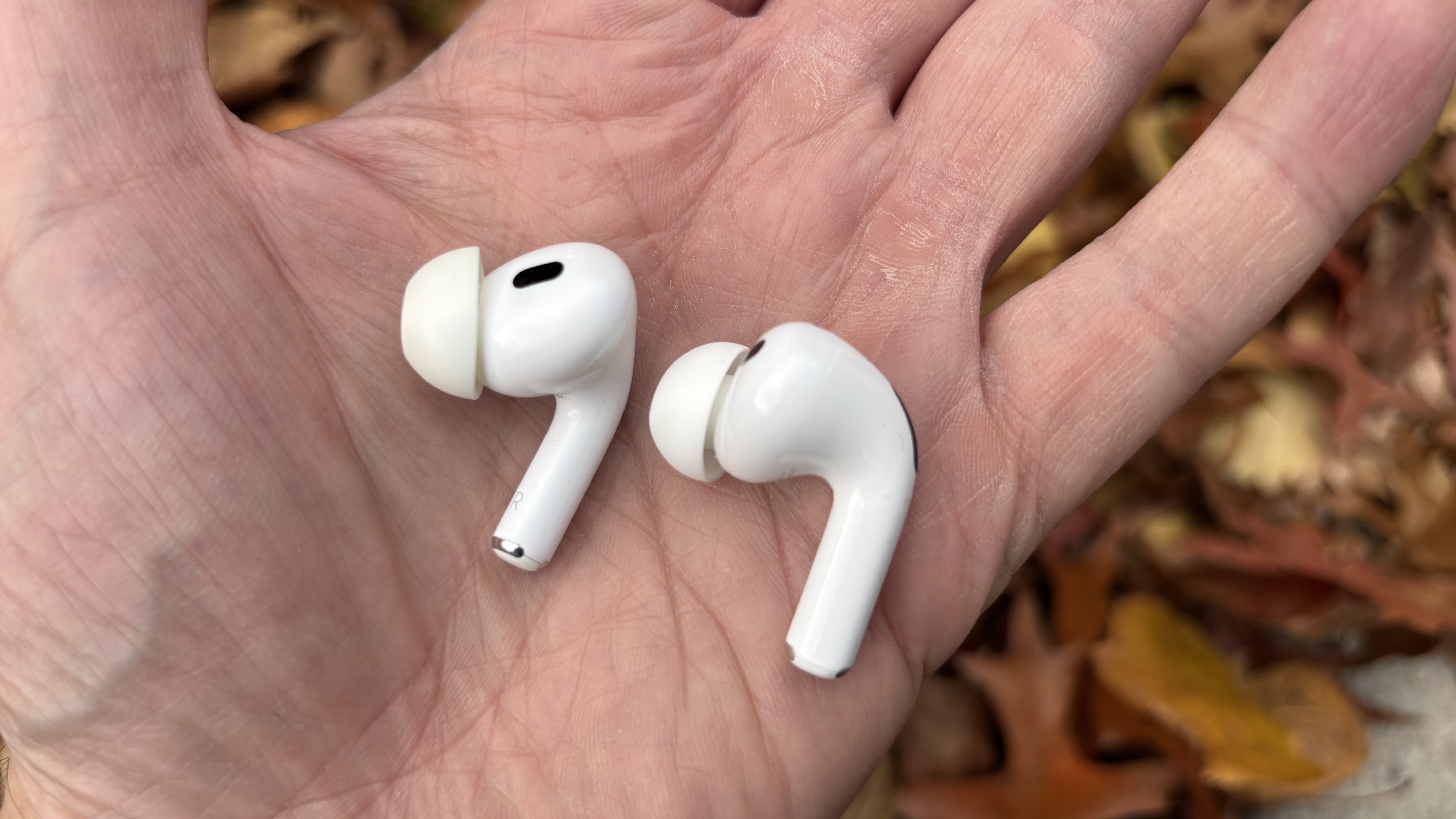 One AirPods Pro 2 earbud and one AirPods Pro 3 earbud being held in a hand