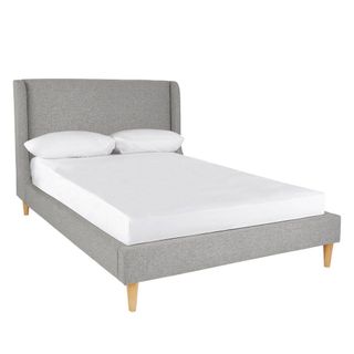 grey bed with white cushions and wooden legs
