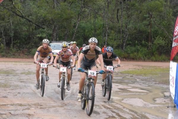 A group of riders roll in to the finish together on a wet day.