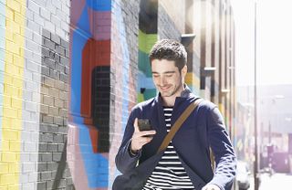 Man walking along the street smiling and text with colourful wall background