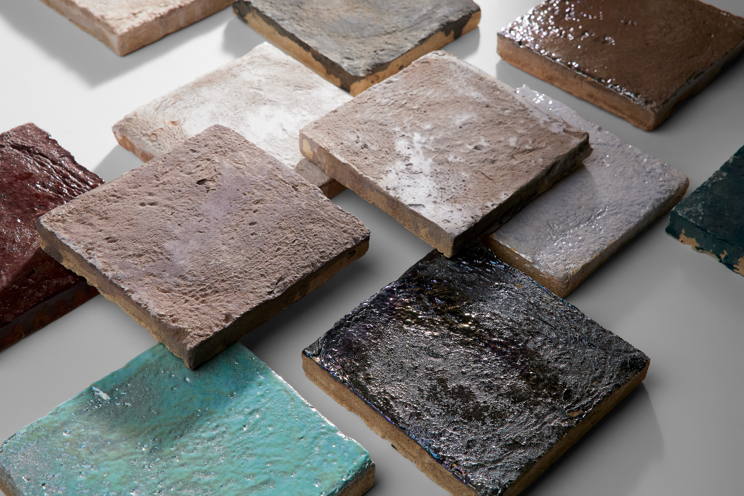 Square tiles in various earthy colors are set on a white surface.