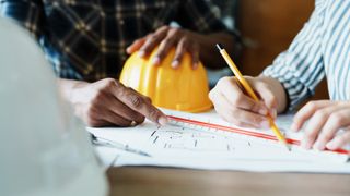 people looking at architectural blue prints on a table