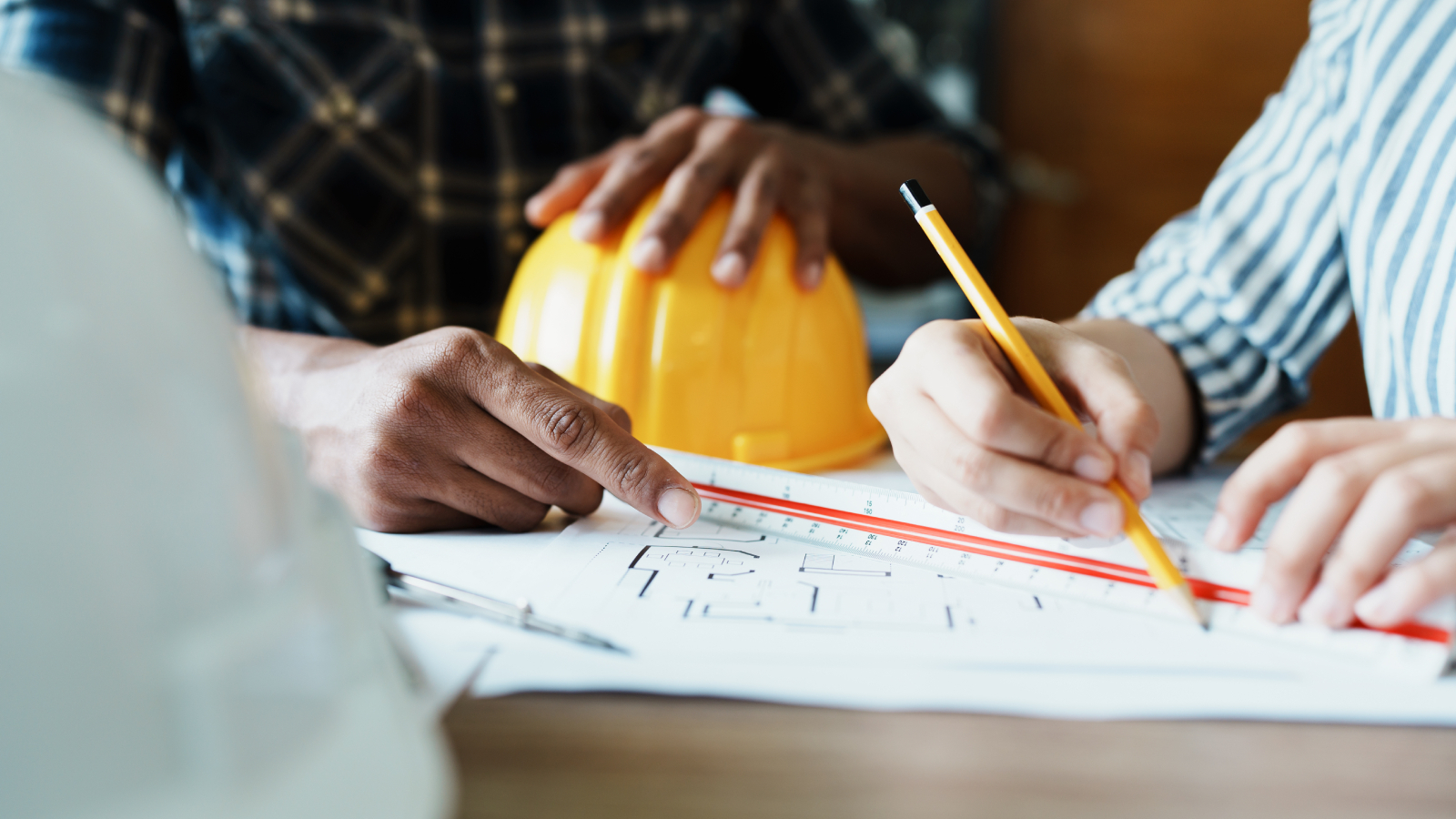 people looking at architectural blue prints on a table