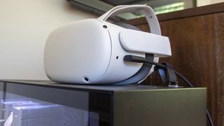 A Meta Quest 2 headset plugged into a gaming PC with an Oculus Link cable