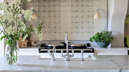 Kitchen backsplash with range in foreground and countertop of island in foreground