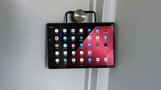 A Lenovo Yoga Tab 13 hanging off a door handle