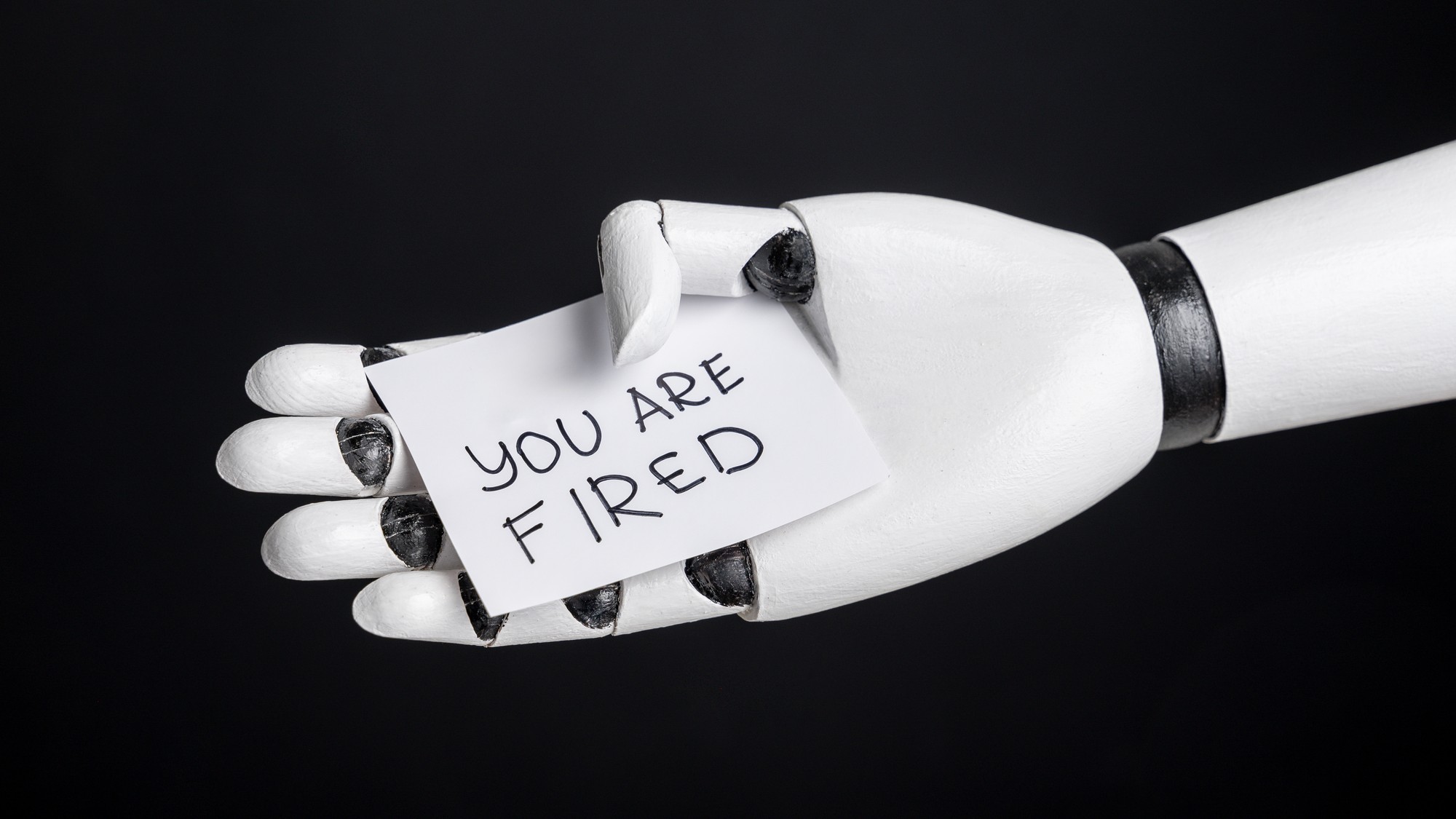 Robot arm holding &ldquo;you are fired&rdquo; slip