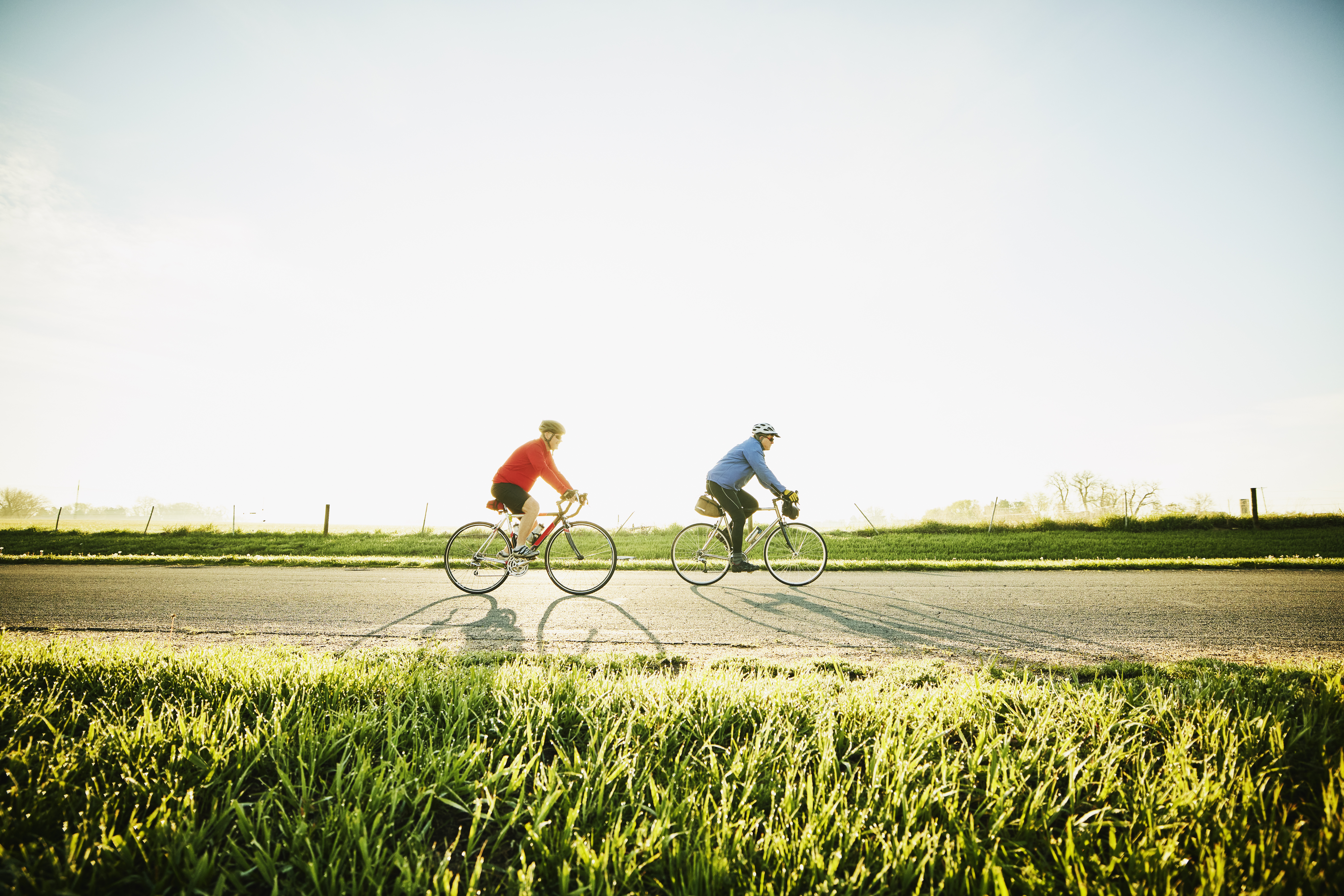 two cyclists on road bikes in a sunny scene