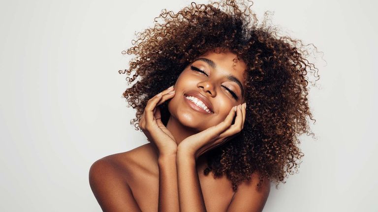 Stock photo which shows a beautiful smiling woman with afro curly hair