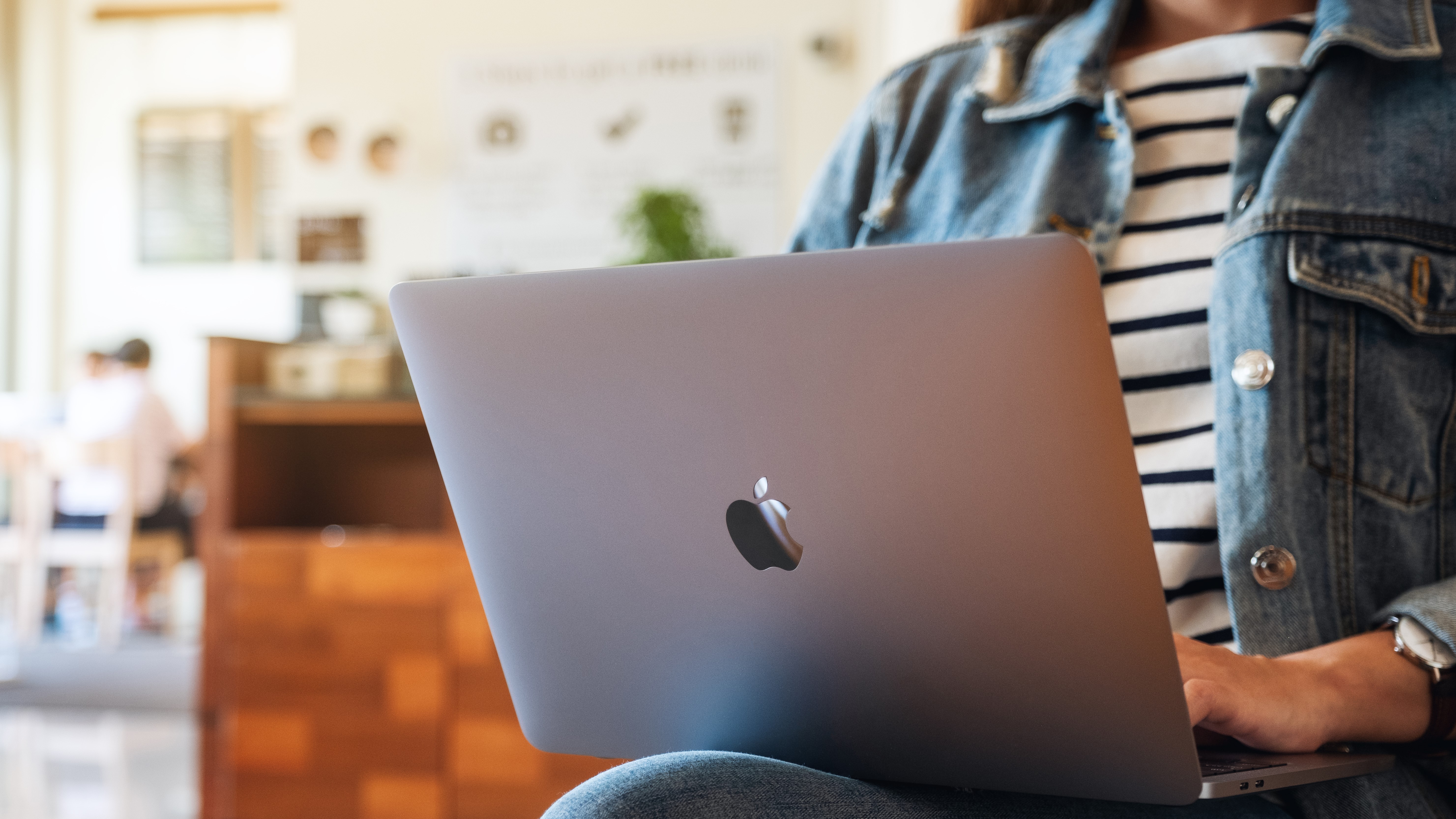 A woman sitting down with a MacBook laptop her lap