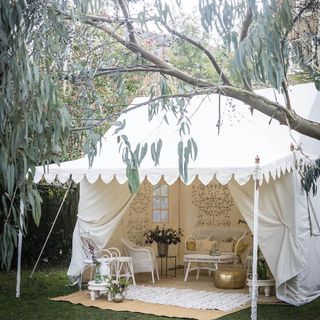 white tent in garden with white rattan furniture