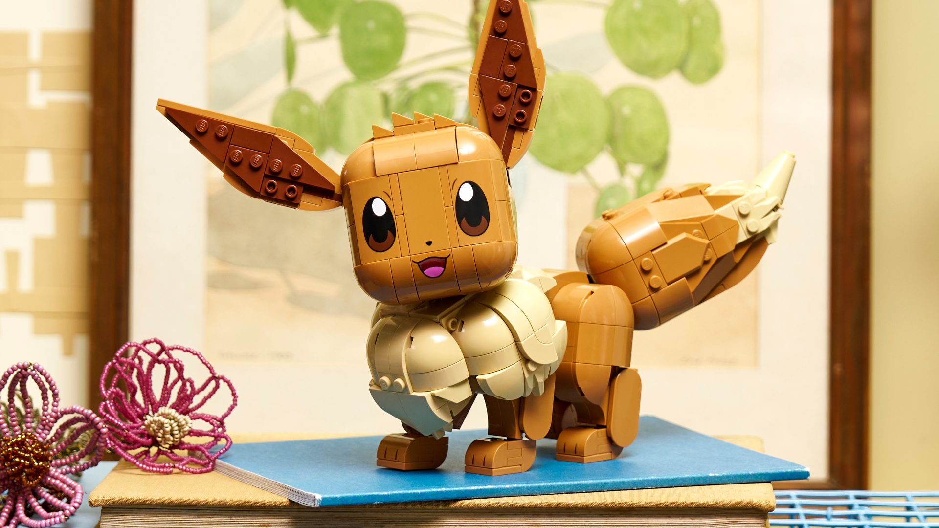 Lego Eevee set on a book beside some fabric flowers