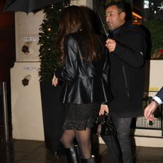 Amal Clooney walks down the street wearing black knee-high heels boots with tight and a minidress.