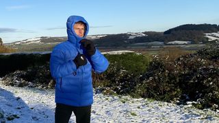 Man wearing Fjällräven Expedition Mid Winter Jacket with the hood up in the snow