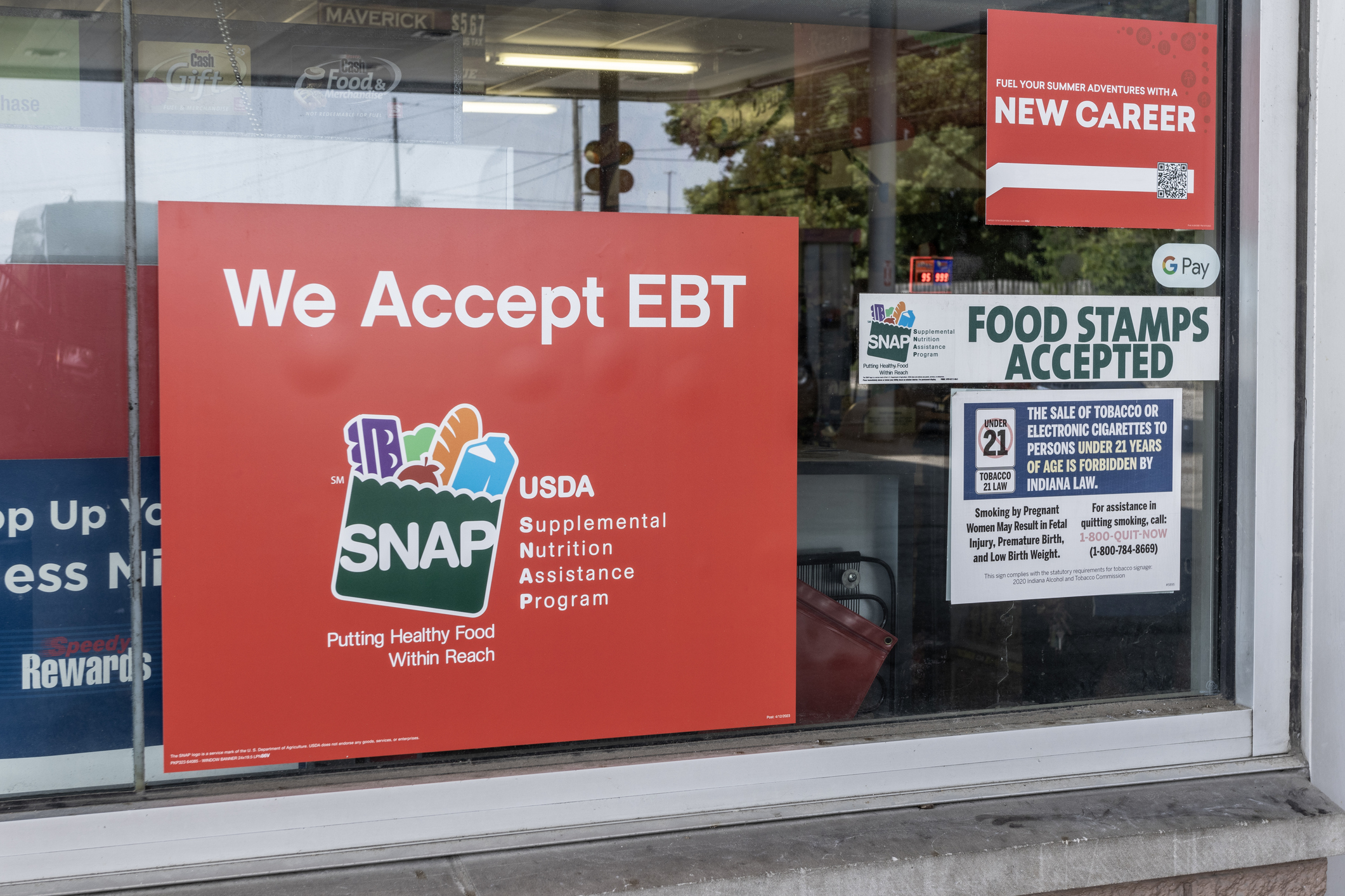 Image shows a sign that reads: SNAP and EBT Accepted here. SNAP and Food Stamps provide benefits to help the budgets of disadvantaged families.