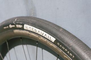 A black large road bike tyre against a stone wall