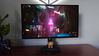 Alienware AW2725DF monitor with Cyberpunk 2077 gameplay on screen featuring neon sign with HDR on