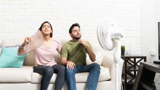 Couple who are too hot in front of fan