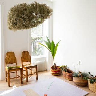 White room with large windows and wooden chairs and woven baskets and plants