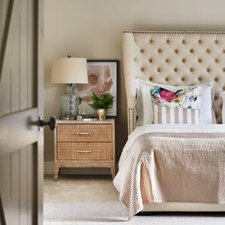 neutral bedroom with large bed, rattan bedside table and rustic decor