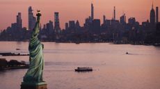 The Statue of Liberty and New York City skyline at dusk.