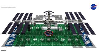 the international space station hovers above an american football field. They are the same size.