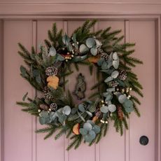 Christmas wreath with eucalyptus leaves and foliage on pink front door