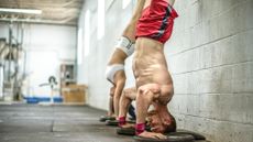 Man and woman performing a handstand at a gym