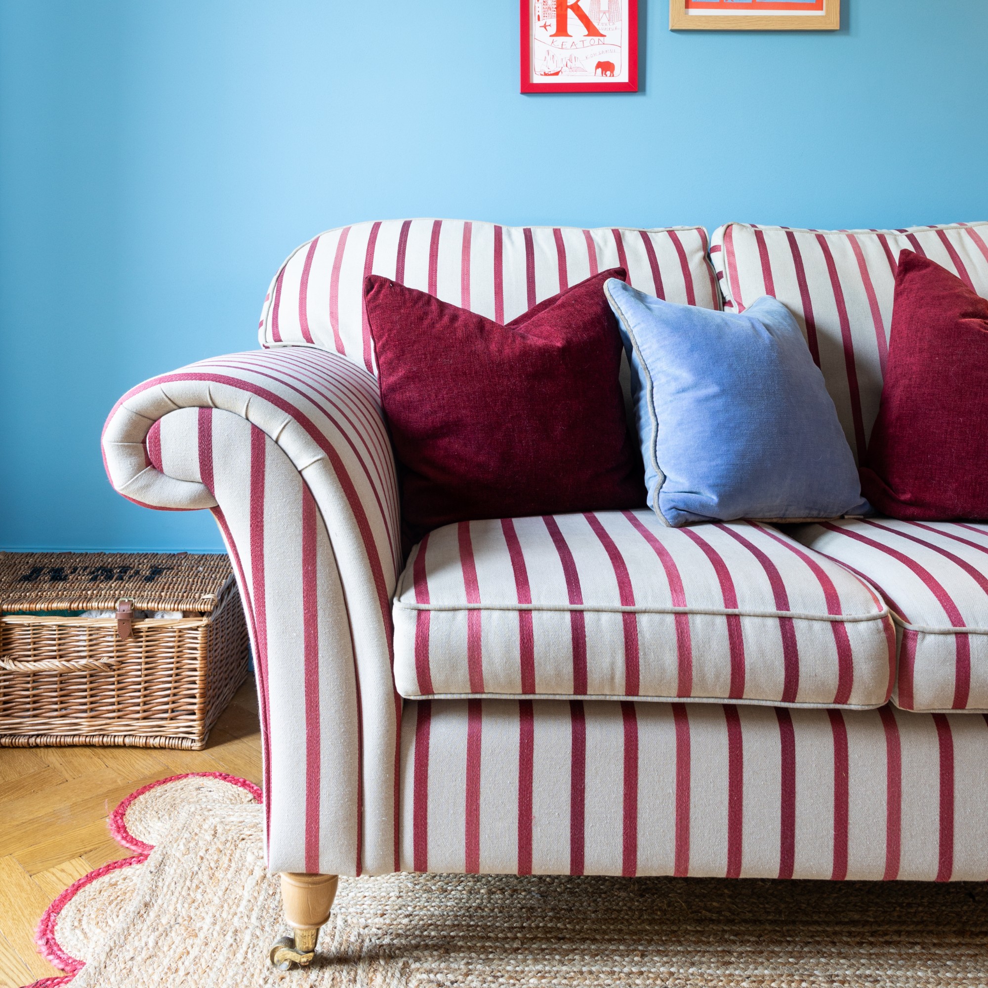 Blue living room with a striped sofa and a scalloped jute rug