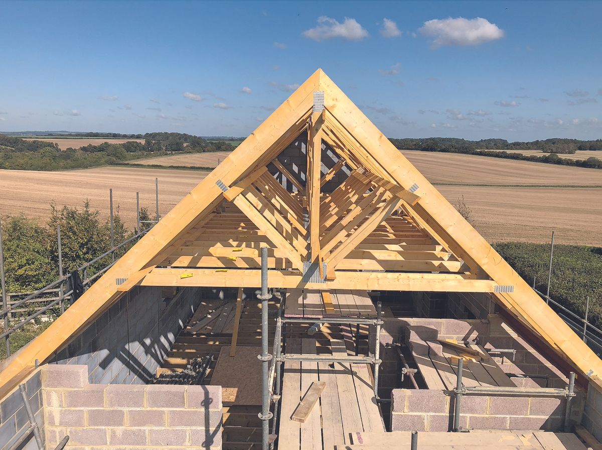 Timber roof trusses being positioned and installed on a house condtruction site