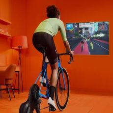 Woman on a indoor bike in front of a TV using Zwift