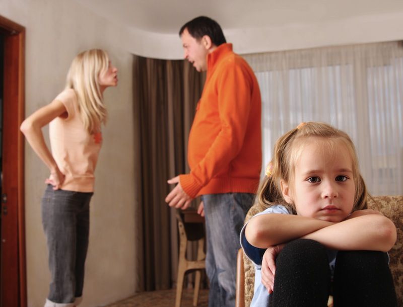 A child sits by as parents argue.