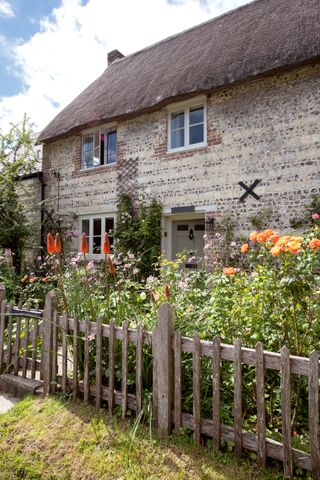Thatched cottage with old fence and cottage garden and best listed home winner in Period Living home of the year awards 2021