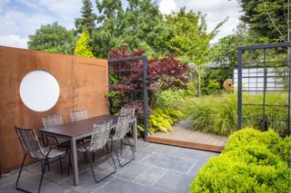 Black square trellis frames an outdoor seating area on a patio