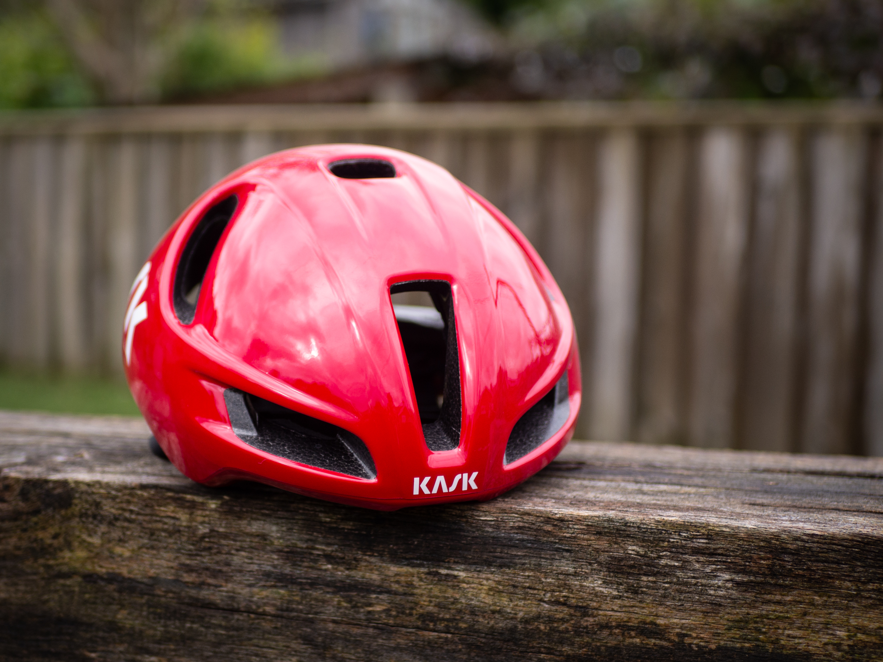 A red Kask Utopia Y aero helmet sits on a wooden bench