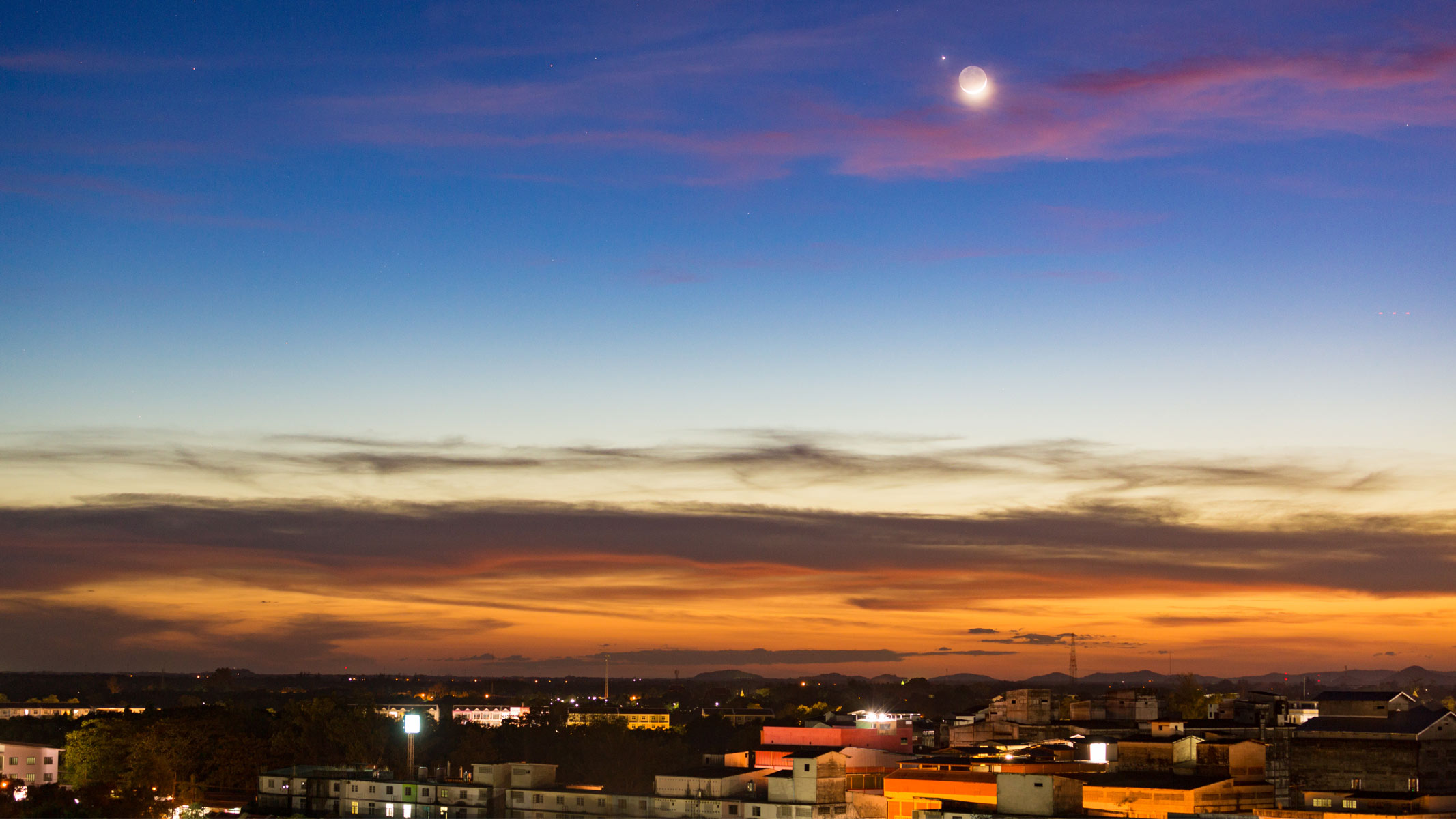 A picture of a town with a twilight sky and moon.
