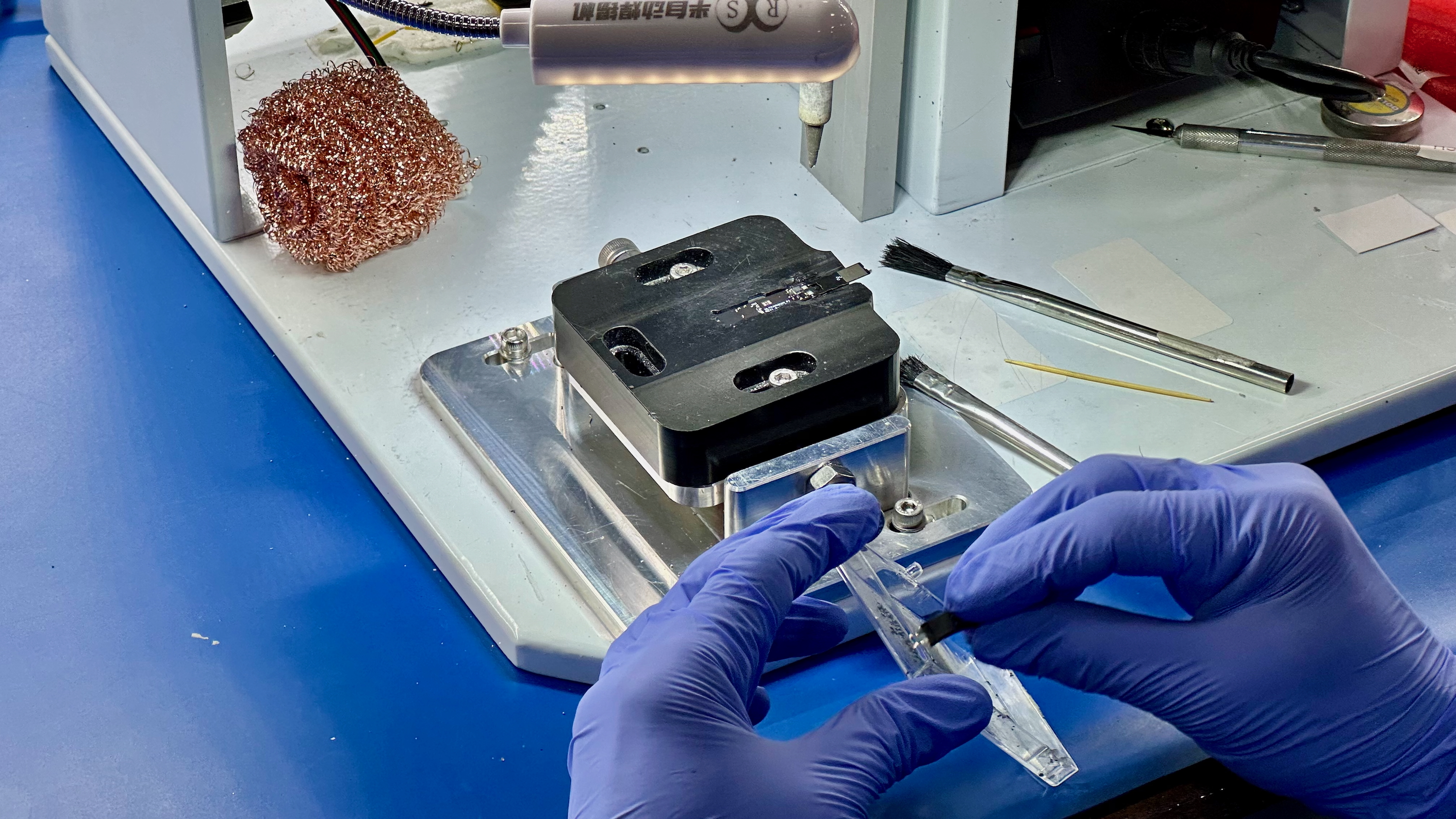 An Ultrahuman factory worker preparing to adhere a battery component to the Ring Air PCB.