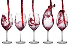 Red wine being poured into glasses from a height