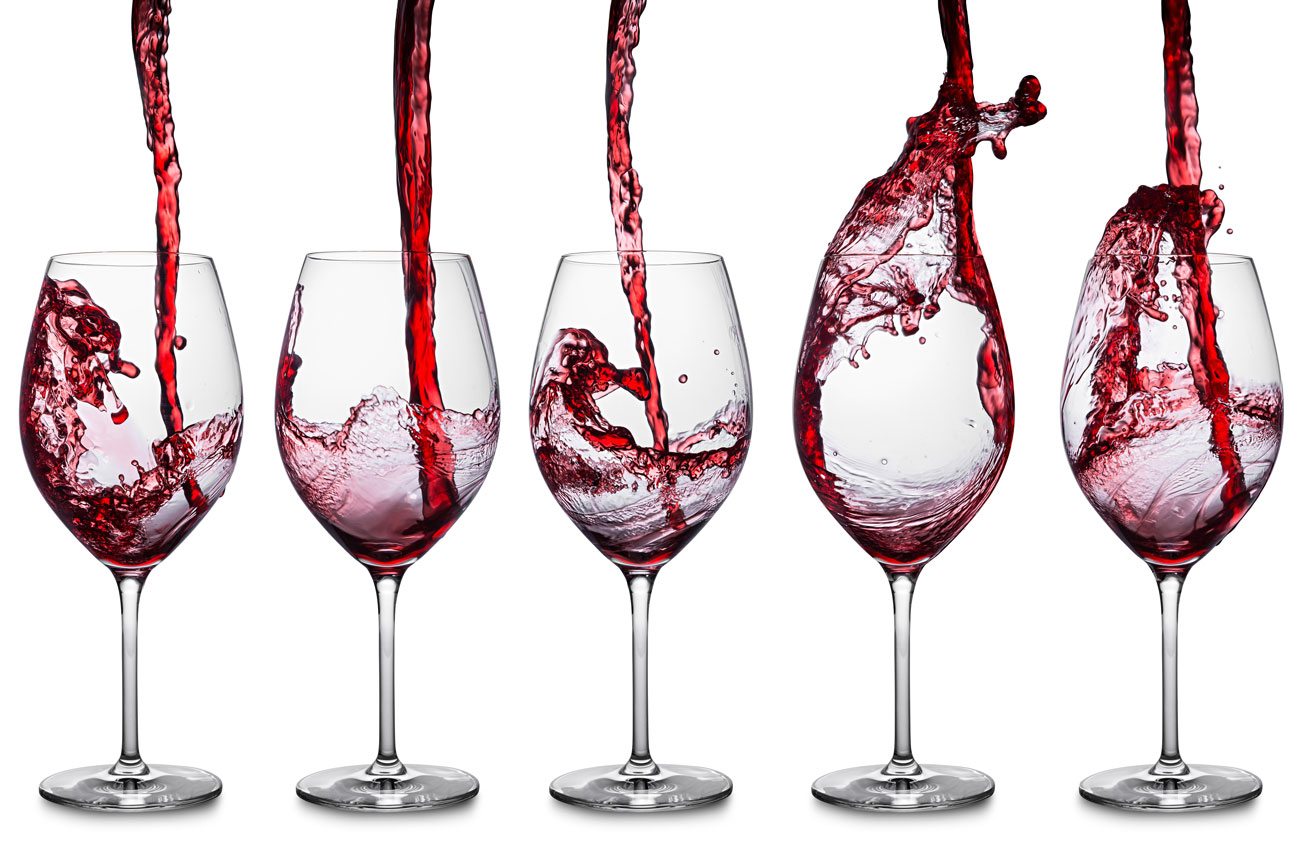 Red wine being poured into glasses from a height