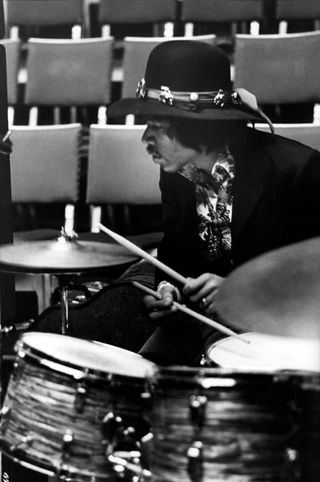 Jimi Hendrix performing on stage, playing drums