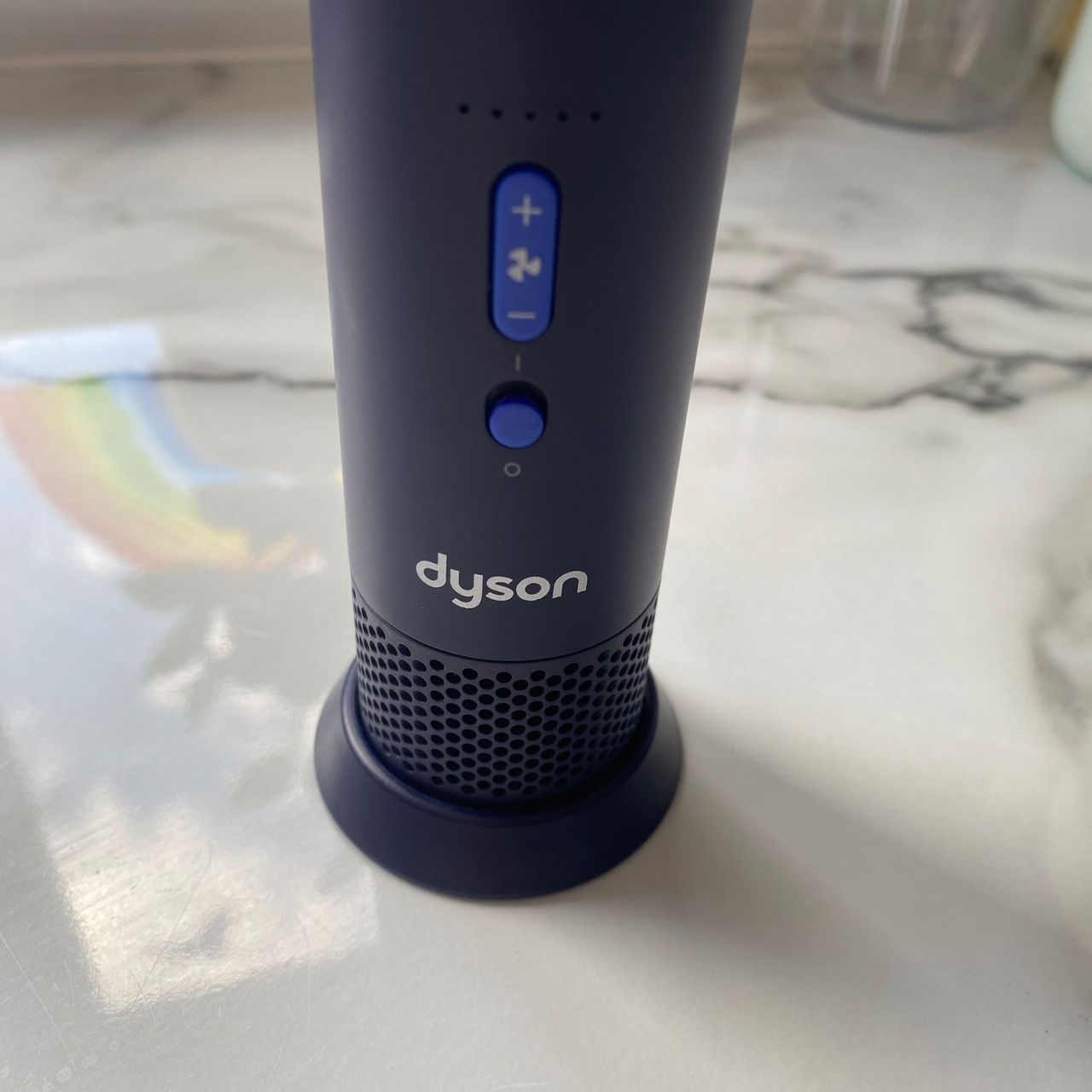 Dyson HushJet Mini Cool fan standing in the charging stand on a marble look worktop