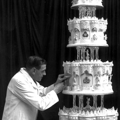 A man putting detail on Queen Elizabeth's wedding cake