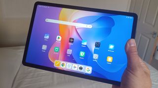 Hand holding Redmi Pad 2 in bedroom