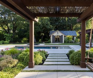 View of modern backyard pool through wooden pergola