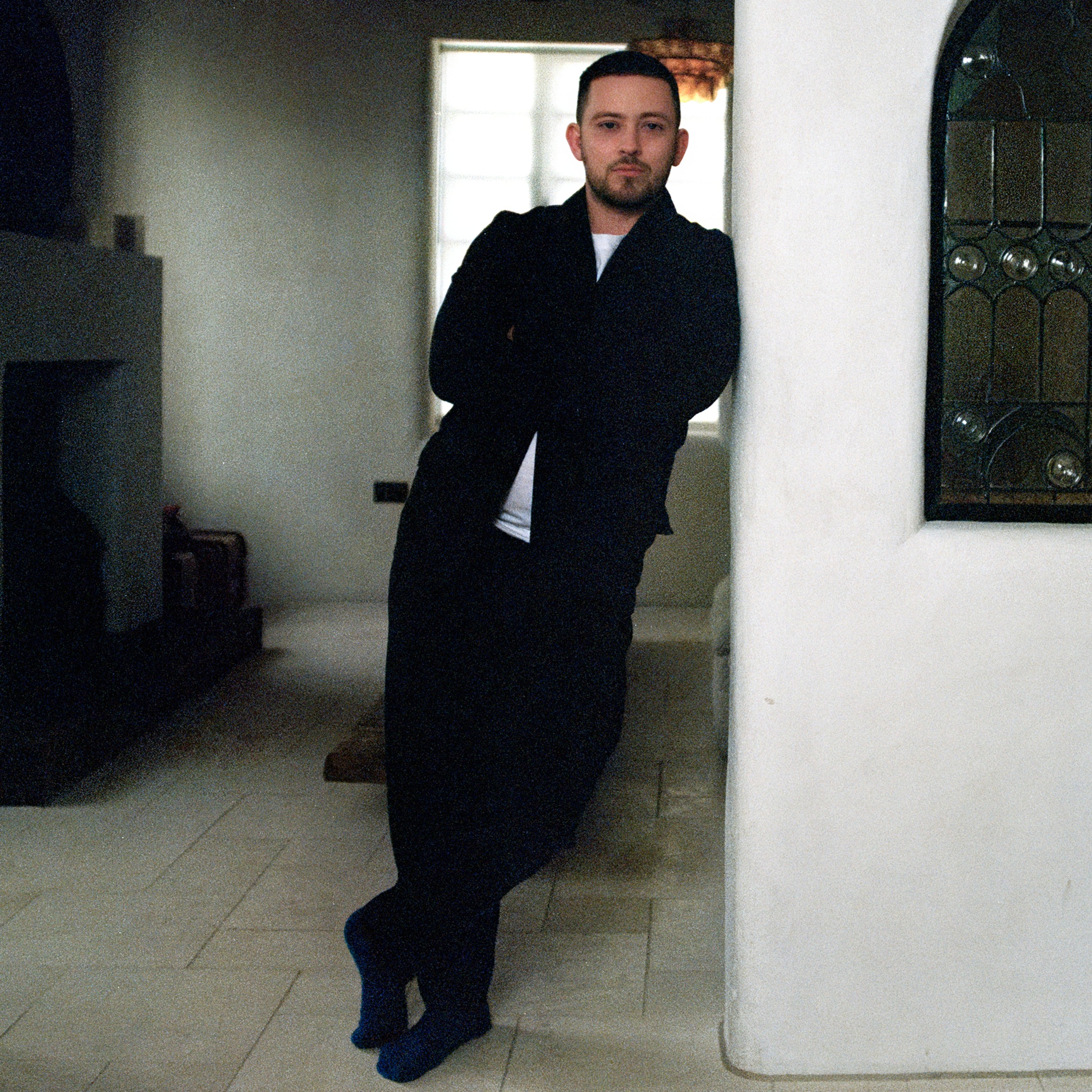 Jobe Burns and artist and designer leans against a wall with an interior window