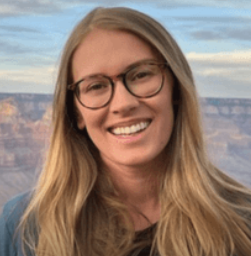 woman with blonde hair wearing glasses smiling to camera