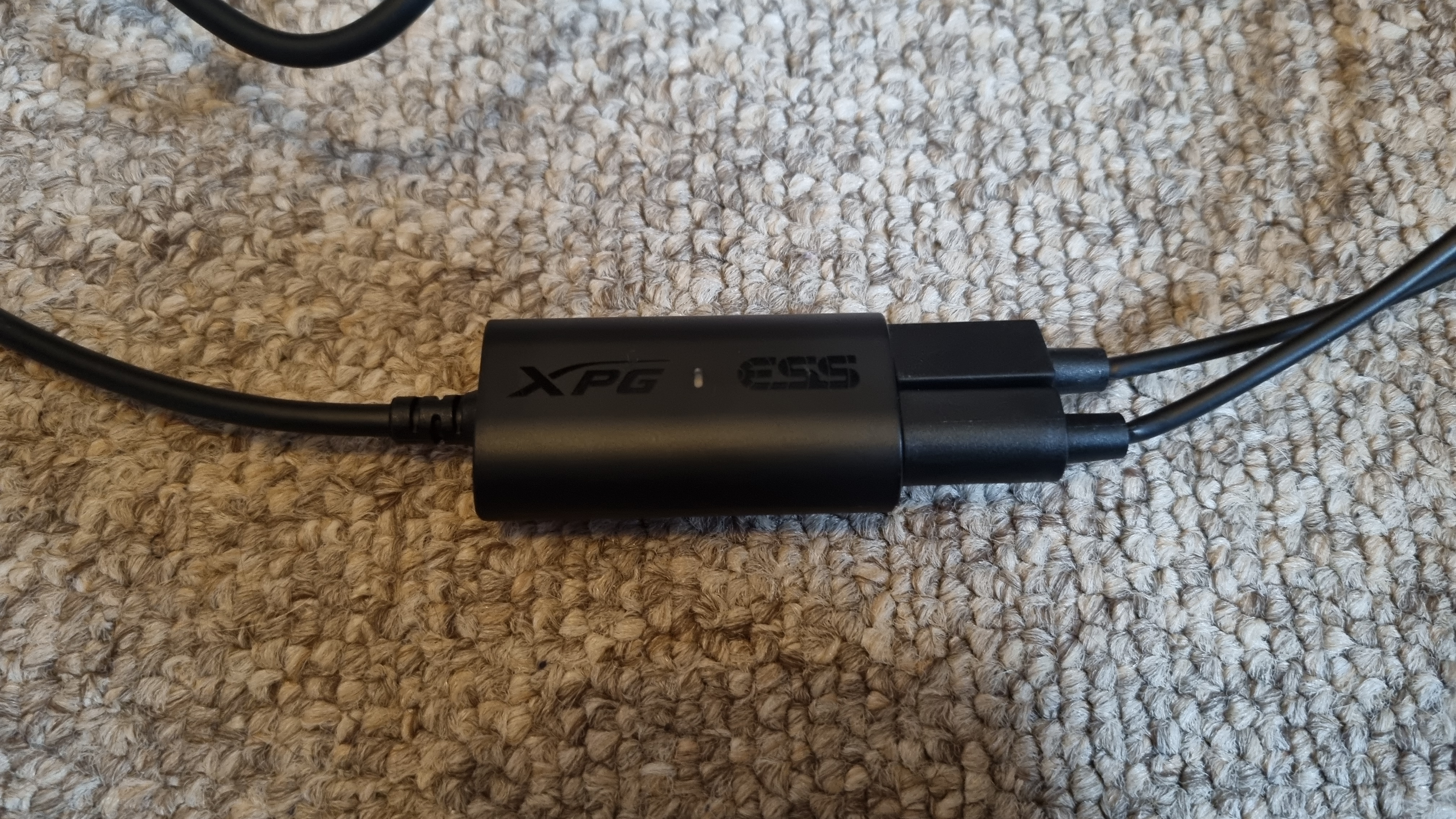 The DAC adapter of the XPG Precog Studio, with two jack cables inserted, on carpet.