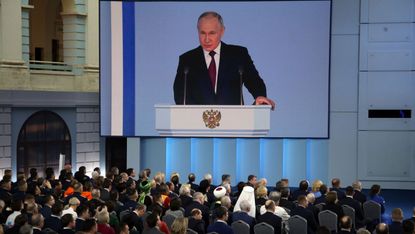 Putin, projected on a screen, speaking during his annual meeting with the Federal Assembly